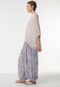 Lichtroze oversized top met korte mouwen, gecombineerd met losse, pastelgekleurde broek met aquarelpatroon. Zachte stof en ontspannen silhouet.