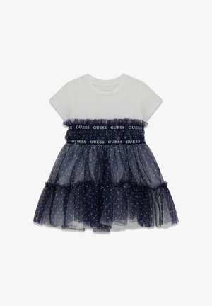 Weißes Baumwoll-T-Shirt mit marineblauem Tüllrock. Der Rock verfügt über Polka-Dots und einen gerafften Saum mit elastischem, markenbedrucktem Bund.