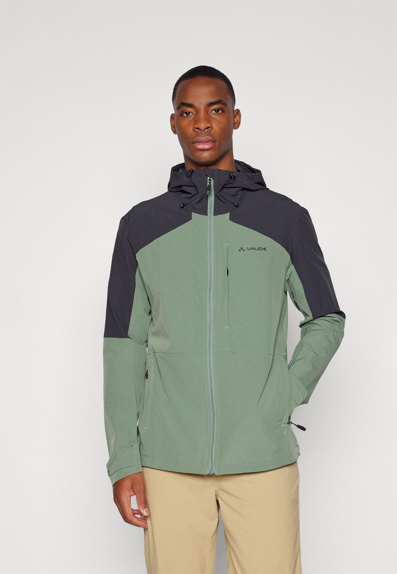 Veste zippée verte et noire avec capuche. Présente un design géométrique, des poches latérales et des cordons de serrage à l'ourlet ajustable. Texture lisse.