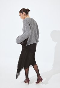 Pelēks pūkains cropped džemperis, melna asimetriska kleita ar ziedu maliņām, caurspīdīgas melnas zeķbikses un bordo augstpapēžu apavi.