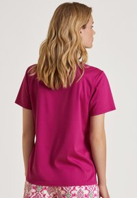 Korte mouwen magenta t-shirt met een gladde textuur, ronde halslijn en een nette zoom. Draag het met gestreepte shorts.