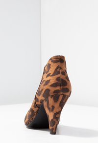 Lederne Schuhe mit Leopardenmuster, ausgestattet mit einem Material aus braunem und schwarzem Wildleder, einer konischen Silhouette und einem konischen schwarzen Absatz.