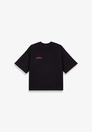 Camiseta negra de gran tamaño con mangas cortas, hecha de algodón, que presenta el texto bordado en rojo "GRMY" en el área del pecho izquierdo.