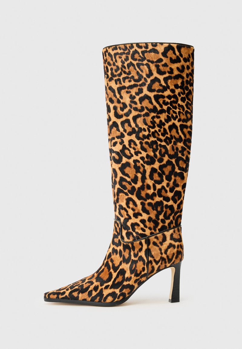 Botte montante en imitation léopard, avec un bout pointu, en matière semblable à du daim, présentant un talon aiguille noir et une silhouette élégante.