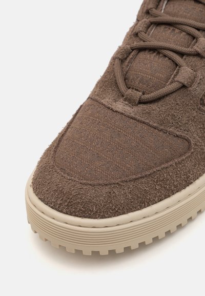 Ruskea mokkanahkakengät, joissa on teksturoitu päällinen, kuvioitu kangas, pyöreät nauhat ja paksu beige kumipohja.