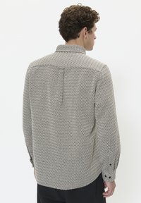 Cămașă cu nasturi, într-un model geometric texturat, crem și negru. Are un guler standard, mâneci lungi și manșete cu nasturi.