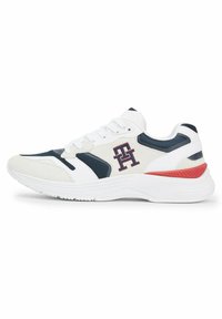Zapatilla deportiva blanca y azul marino con parte superior de malla, collar acolchado, logo bordado y suela texturizada con un acento rojo.