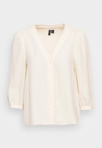 Cremefarvet bluse med V-hals, blondekant langs knapstolpen og trekvartlange pufærmer. Glat, letvægtsstof.