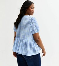 Blau-weiß kariertes Bluse im Gingham-Stil mit Puffärmeln und einem Peplum-Saum. Weicher Stoff mit lockerer Passform, getragen mit dunklen Jeans.