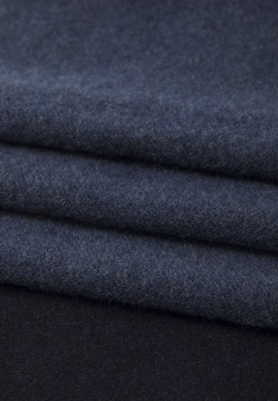 Tissu en laine sombre, plié, présentant une surface texturée. Deux nuances : bleu marine profond avec une légère nuance chinée et un noir uni en dessous.