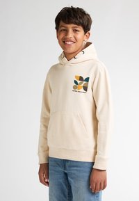 Felpa beige con cappuccio e tasca a marsupio, caratterizzata da una grafica geometrica colorata sul lato sinistro del petto e cappuccio con cordini.