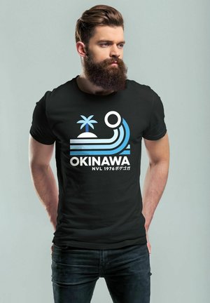 Schwarzes Baumwoll-T-Shirt mit einem grafischen Design, das blaue Streifen, eine Palme und den Text "OKINAWA NVL 1976" in Weiß und Blau zeigt.