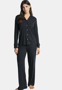 Ensemble de pyjama noir avec manches longues et pantalon, doté d'un devant boutonné, d'une poche poitrine et d'une texture côtelée. Convient confortablement.