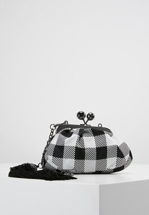 Zwart-wit ruiten stoffen clutch met een ronde metalen gesp, kettingriem en een tassel detail. Getextureerd materiaal, zachte vorm.