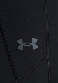 Leggings neri a compressione con una superficie liscia e una leggera lucentezza, caratterizzati da cuciture visibili e un logo grigio chiaro sulla coscia.
