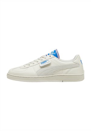 Biały sneaker Puma Super Team z niebieskim logo na języku i pięcie, bocznym paskiem Puma oraz białą gumową podeszwą.
