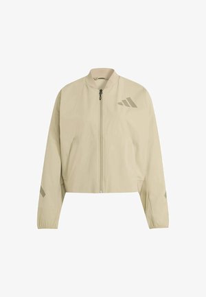 Chaqueta beige recortada con cierre de cremallera, cuello de canalé y puños elásticos. Presenta un discreto logo estampado y dos bolsillos frontales. Textura suave.