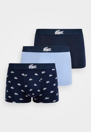 Tres pares de bóxer para hombre en azul marino, azul claro y azul marino con logos de cocodrilo blancos, cintura con la marca visible en cada uno.