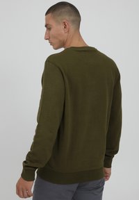 Olivenfarget genser med lange ermer, ribbede mansjetter og hem. Glatt tekstur, klassisk rund hals-design. Enfarget stoff.