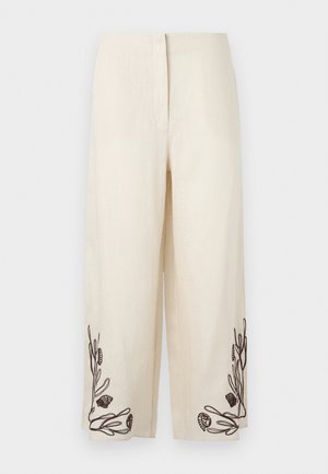 Krémové nohavice so širokými nohavicami s čiernymi vyšívanými motívmi morských rias a mušlí blízko lemu na oboch nohaviciach.