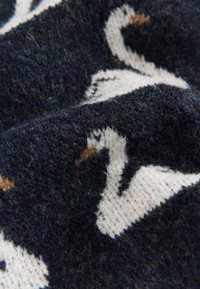 Stickat tyg med en mörk marinblå bakgrund med ett mönster av vita svanar och bruna inslag. Mjukt och texturerat ytfinish med synliga fibrer.