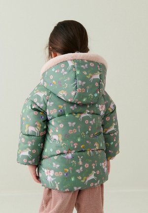 Enfant portant une veste matelassée verte à capuche, ornée d'illustrations de licorne, papillon, fée, grenouille et fleur, vue de dos.