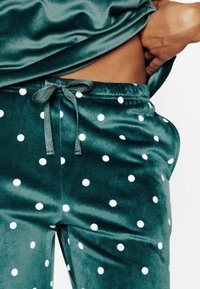 Ensemble de vêtements d'intérieur en velours de couleur vert foncé avec des pois blancs, comprenant une taille élastique et un cordon de serrage pour un ajustement personnalisé.