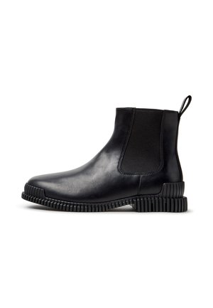 Bottine en cuir noir avec panneau latéral élastique, semelle épaisse texturée et languette au talon, présentée de profil sur fond blanc.