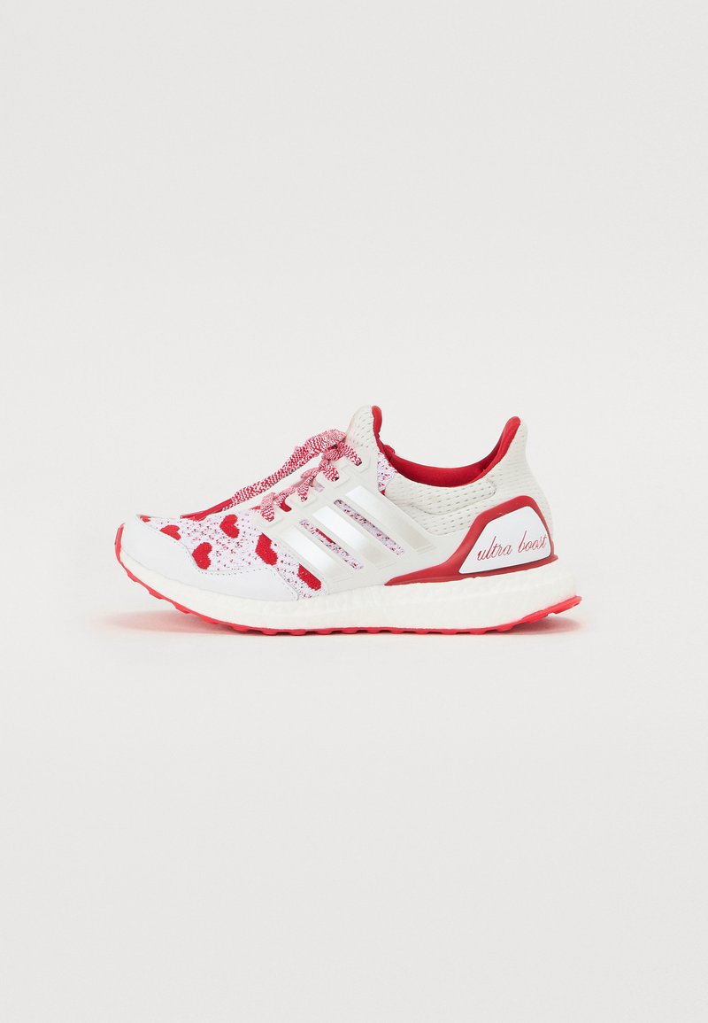 Bijela trkačka cipela s crvenim akcentima, mrežastim gornjim dijelom, teksturiranim vezicama i podstavljenim potplatom. Ima tri bijele pruge i "ultra boost" na peti.