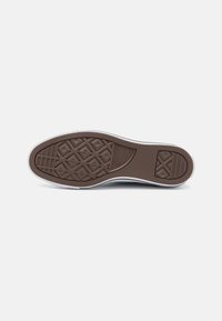 Sola de sapato de borracha castanha com um padrão de diamante e acentos laterais brancos. Inclui áreas texturizadas e detalhes do logotipo perto do calcanhar.