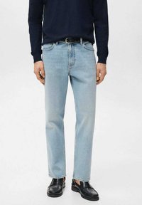 Vaqueros de mezclilla azul claro con corte recto, diseño de cinco bolsillos y costuras en contraste, combinados con un suéter oscuro y zapatos negros.