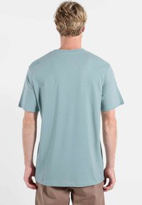 T-shirt à manches courtes bleu clair, mélange de coton, col rond, texture lisse, détail de couture subtil sur le haut du dos.