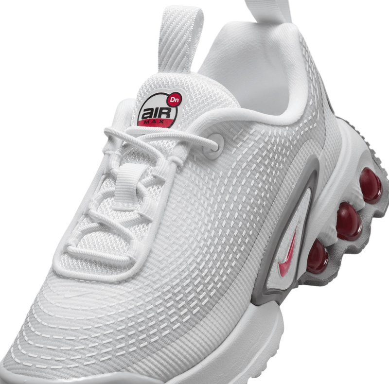 Chaussures de sport blanches avec une tige en maille texturée, des accents gris, des pods d'amortissement en air visibles en rouge, et une étiquette arborant le logo 'Air Max'.