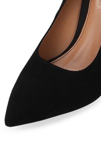 Black suede high heel shoe with a pointed toe and cutout design, featuring a smooth interior lining and subtle stitching details.