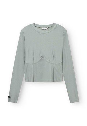 Haut cropped à manches longues en tissu vert clair avec une texture lisse. Il présente une couture centrale et un subtil détail courbé au niveau de la poitrine.