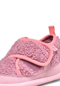 Chausson rose avec une texture duveteuse, doté d'une sangle Velcro et d'une forme douce et arrondie. Le matériau comprend de la fausse fourrure et une semelle lisse.