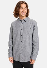 Gray flannel shirt with a button-up design, long sleeves, chest pocket, and dark buttons. Features a small logo on the pocket.