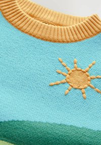 Pletený sveter s telom v svetlomodrej farbe, zlatohnedým rebrovaným golierom a vyšitým motívom slnka. Mäkšia textúra, hravý dizajn a žiarivé farby.