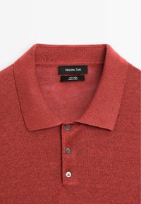 Červená polo košile z lnu s žebrovaným límcem, třemi šedými knoflíky a tkanou strukturou. Štítek říká "Massimo Dutti, 100% len."