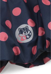 Tessuto blu navy con grandi pois rosa; presenta un logo circolare grigio che raffigura un procione che tiene un oggetto rosso. Texture liscia.