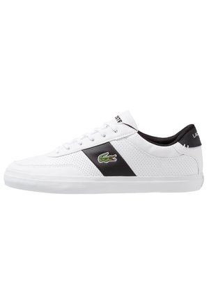 Baskets basses blanches avec une bande latérale noire, le logo crocodile vert de Lacoste, des lacets blancs et une doublure intérieure noire.