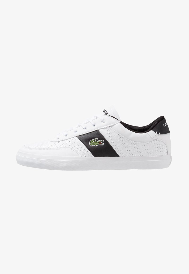Baskets basses blanches avec une bande latérale noire, le logo crocodile vert de Lacoste, des lacets blancs et une doublure intérieure noire.