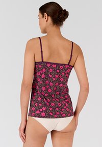 Top senza maniche floreale in viola con motivi rosa e verdi, caratterizzato da spalline sottili e un design aderente. Abbinato a un pantalone chiaro.