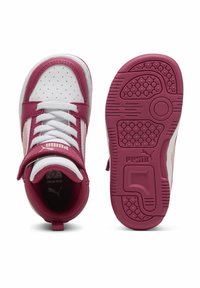 Sneakers violets et blancs avec une tige en cuir lisse, un système de laçage et une semelle en caoutchouc texturé présentant des motifs circulaires et une marque.