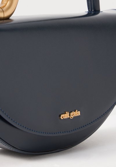 Navy leather handbag with a curved shape, gold hardware, and embossed logo. Smooth texture with contrasting stitching detail.