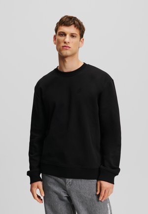 Black sweatshirt made of cotton, featuring a crew neck, ribbed cuffs, and a small embroidered logo on the chest. Casual fit with side seam details.