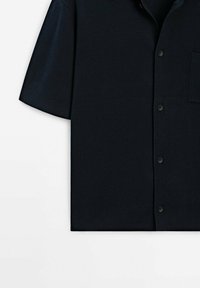 Chemise noire à manches courtes avec boutons, col et poche poitrine, présentée à plat sur fond blanc.