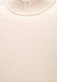 Cremefarbener Pullover mit Rollkragen, der einen gerippten Kragen und eine glatte, weiche Textur aufweist und sich gut zum Schichten in kühlerem Wetter eignet.