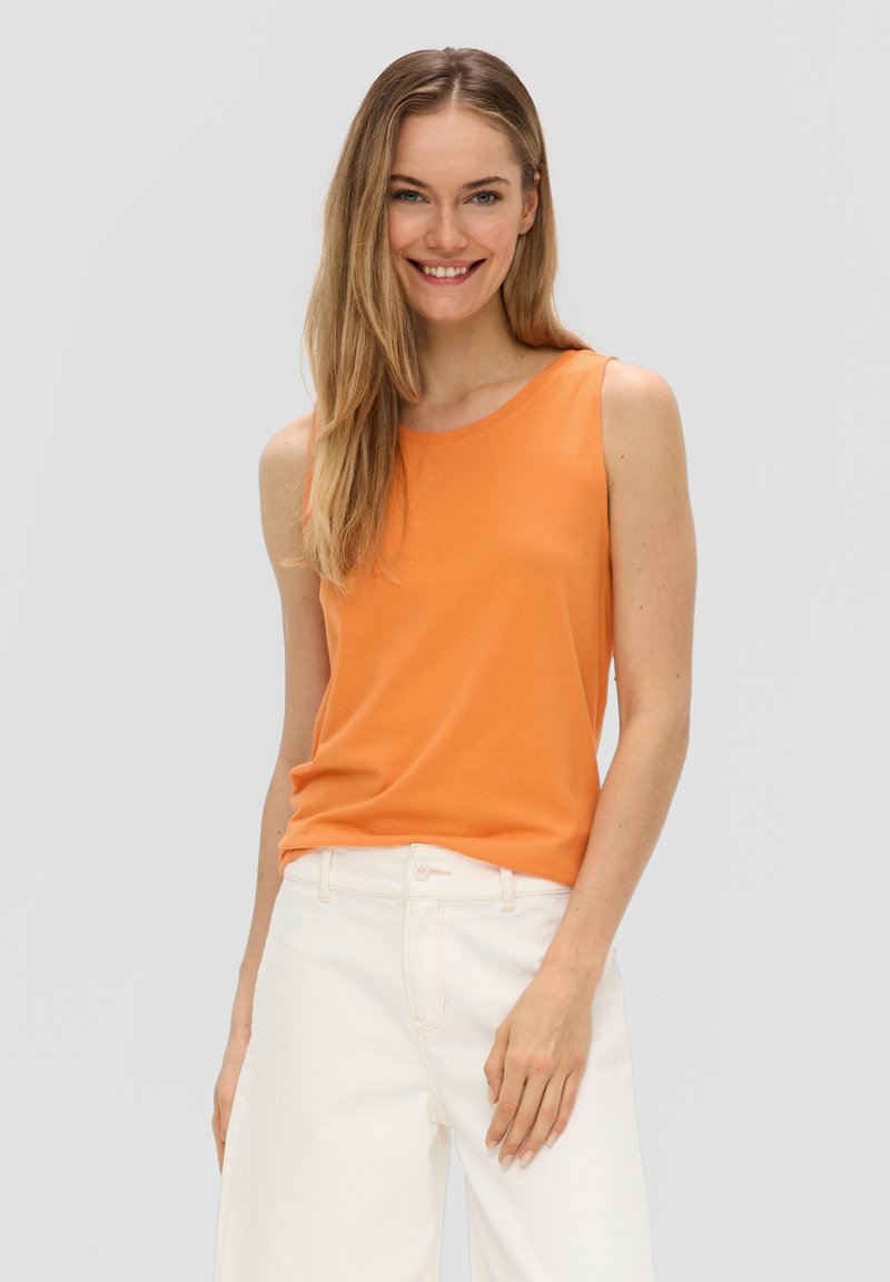 Oranje mouwloze tanktop van zacht materiaal, met een ronde halslijn. Gecombineerd met witte hoge taillebroeken in een ontspannen pasvorm.
