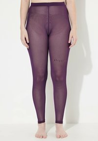 Průhledné fialové legíny s hladkým povrchem, elastickým materiálem a úzkým pasem. Na dolní části nohy je potisk "#TrueSize".